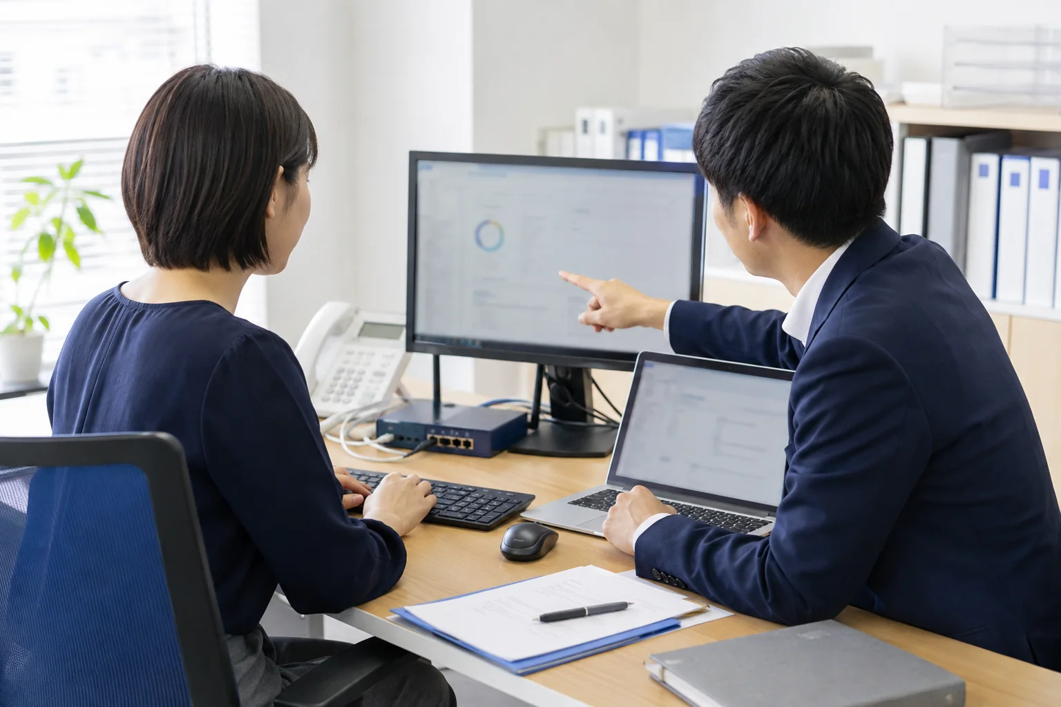企業担当者とIT担当者がPC画面を確認する様子